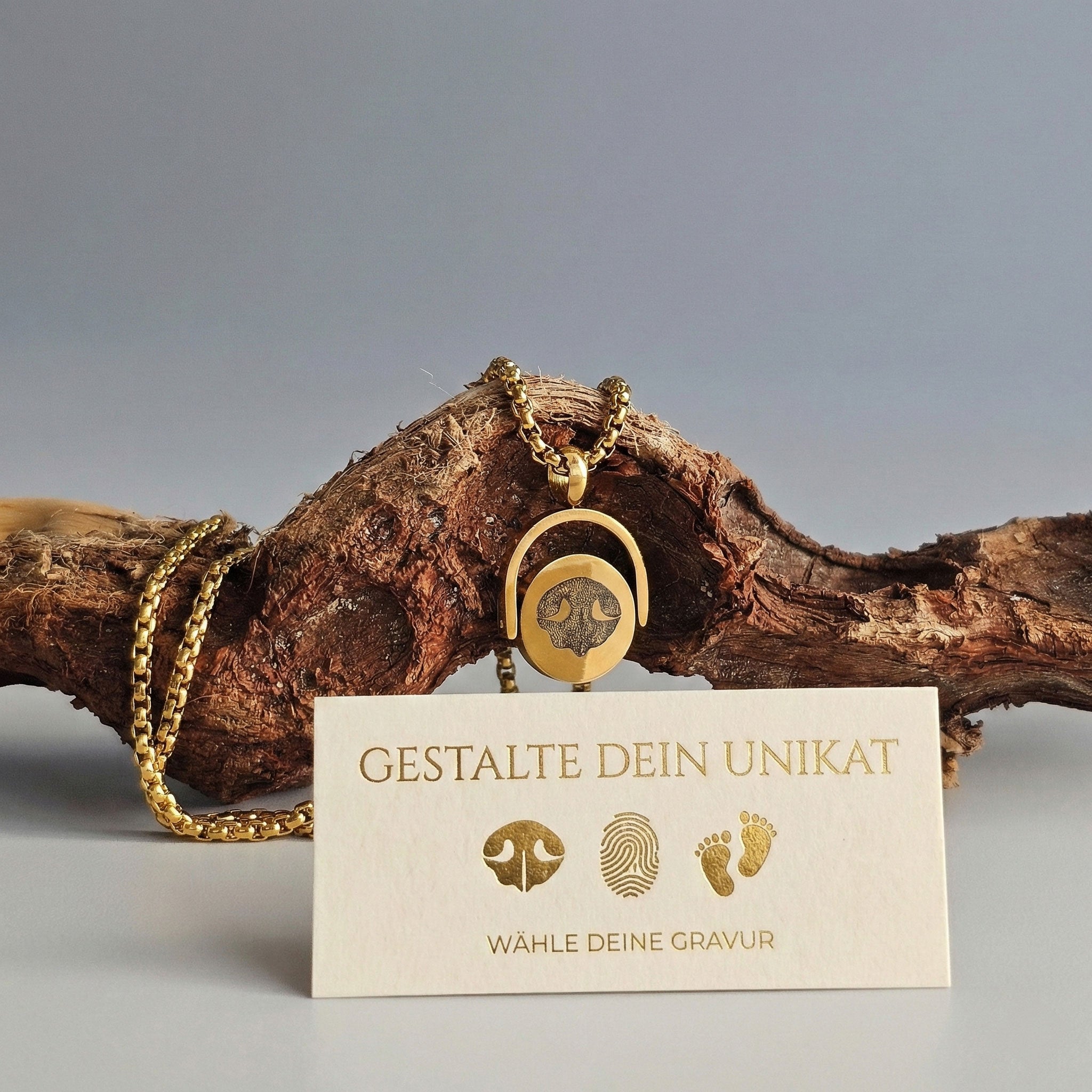 Personalisiertes Steigbügel Drehmedaillon in Gold mit gravierter Hundepfote auf Holzdekor