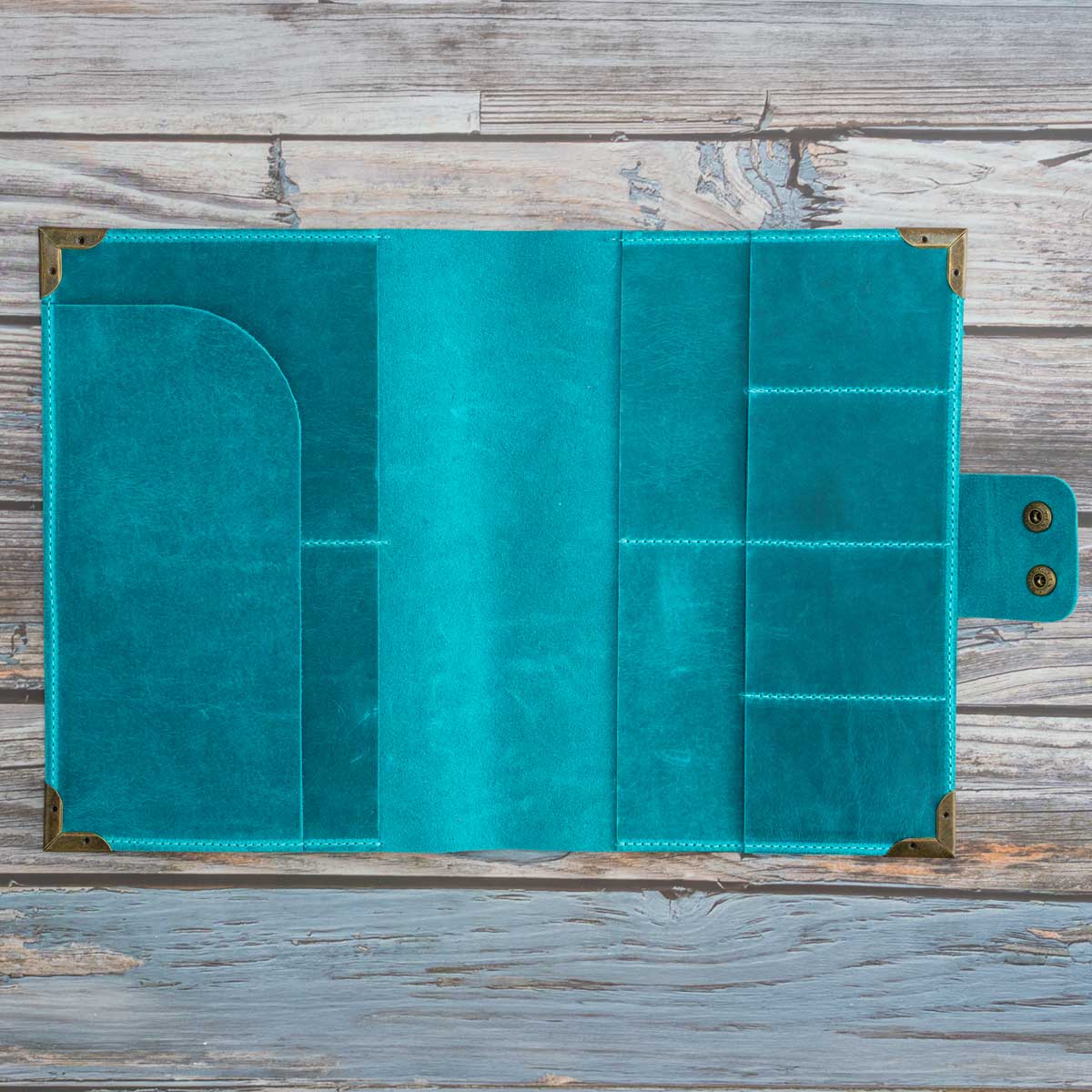 Geöffnete Innenansicht des leeren Travel Wallets. Das türkise Leder zeigt vier passgenaue Fächer für Reisepässe oder Heimtierausweise sowie vier Kartensteckplätze.