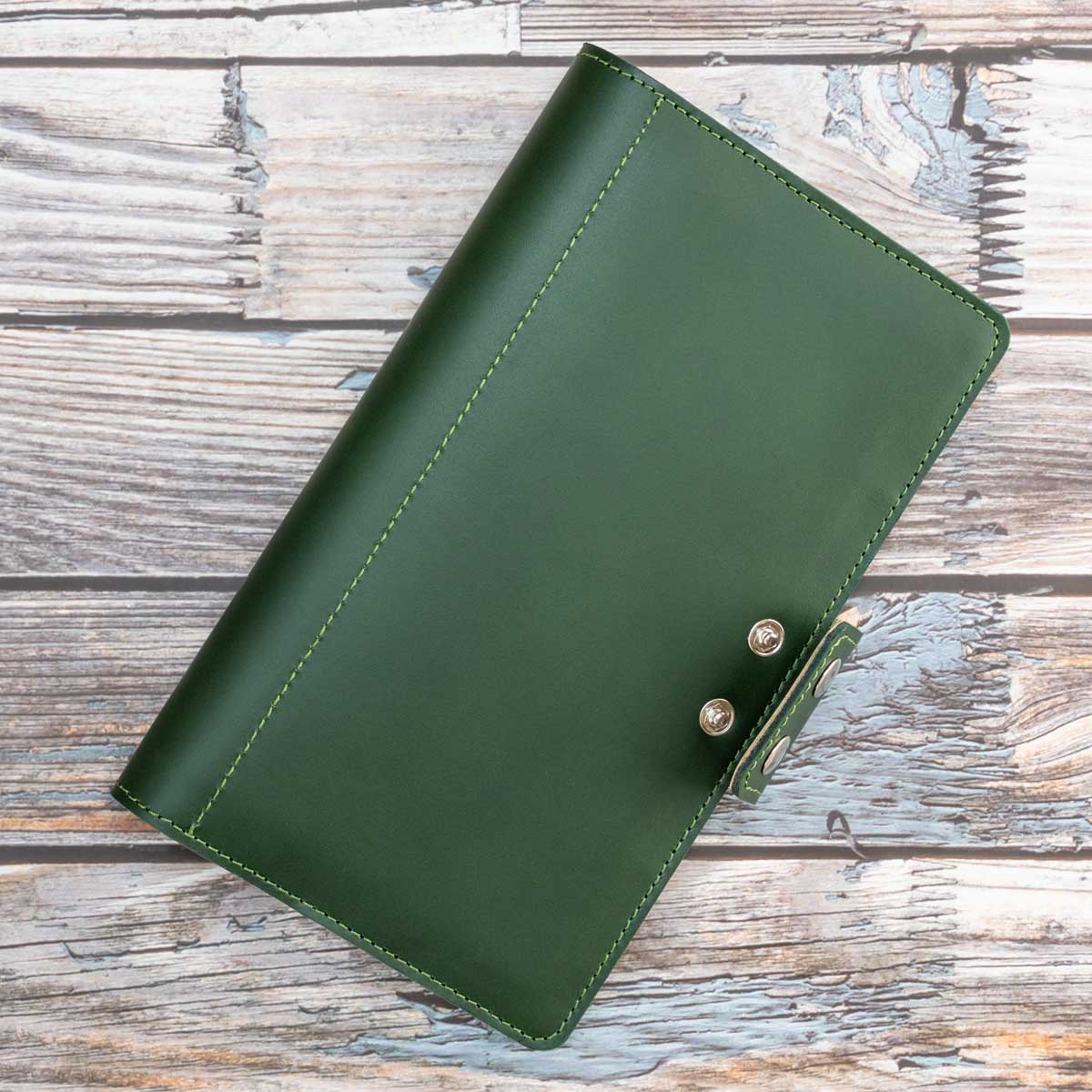 Vertikale Ansicht des dunkelgrünen Travel Wallets. Das robuste italienische Leder und der praktische Doppel-Druckknopfverschluss machen es zum idealen Reisebegleiter