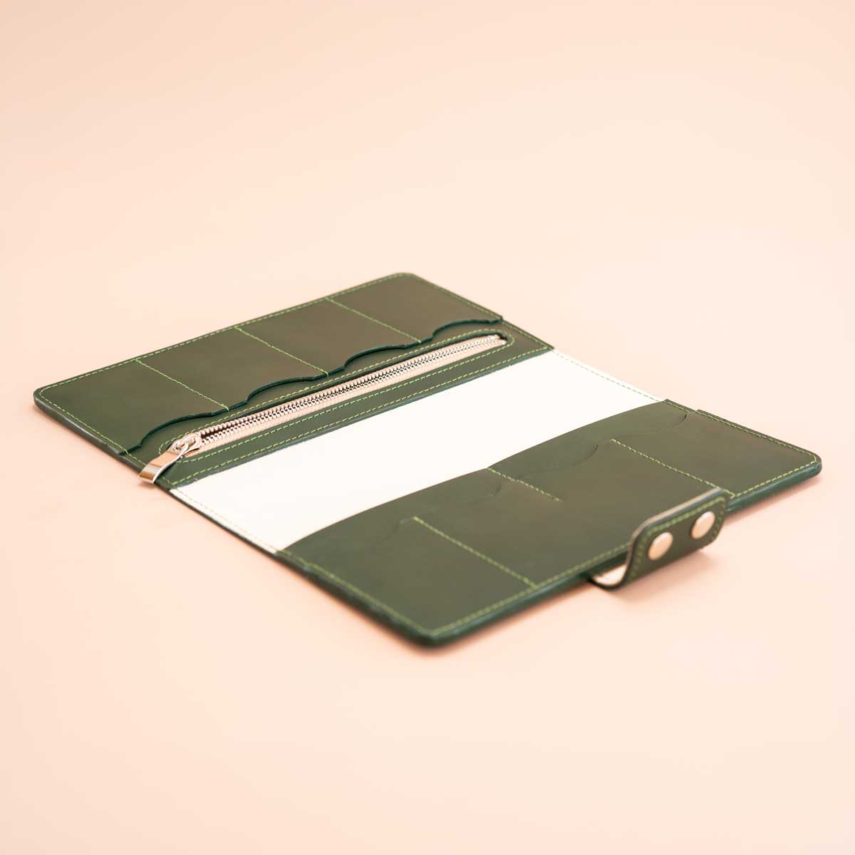 Geöffnetes Reise-Etui aus Leder. Der Innenraum zeigt den eleganten Kontrast zwischen feinstem Kalbsnappa in Off-White und dem dunkelgrünen Taschenleder. Sichtbar sind acht Kartenfächer und ein großes Reißverschlussfach