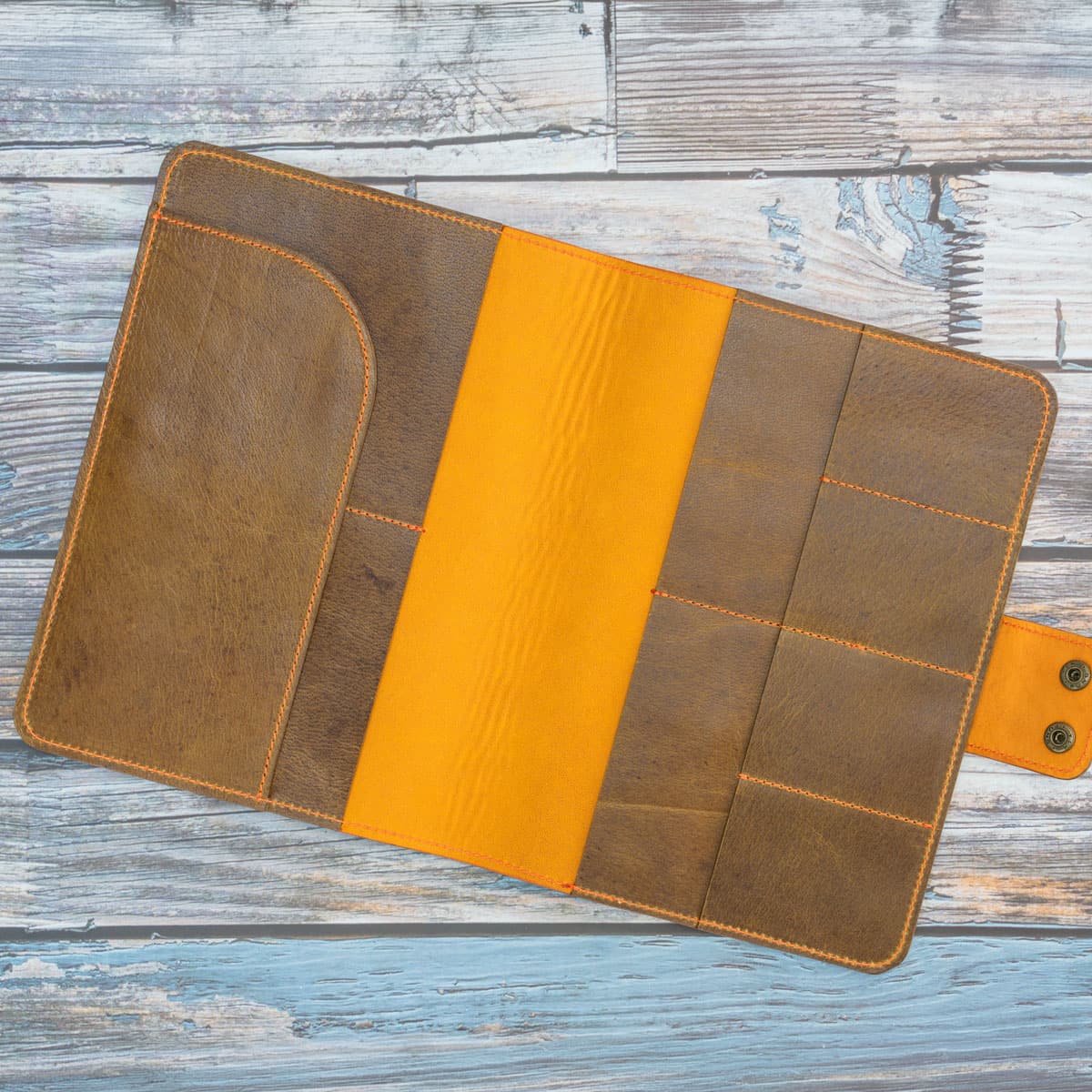 Geöffnetes Travel Wallet ohne Inhalt. Das Innenleben aus weichem orangem Nubukleder zeigt vier großzügige Fächer für Reisepässe, vier Kartenfächer und ein Einschubfach für Dokumente.