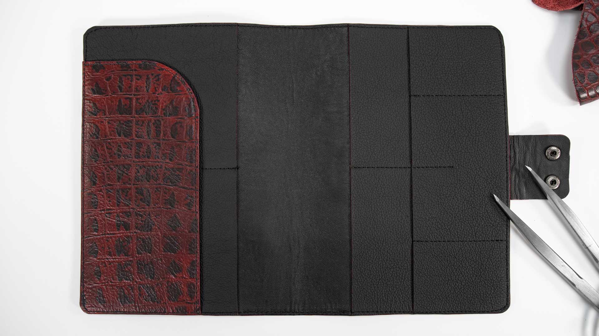 Geöffnetes Reise-Etui aus Leder. Das schwarze Rindsnappa im Inneren zeigt die übersichtliche Aufteilung für vier Pässe, Karten und Reiseunterlagen
