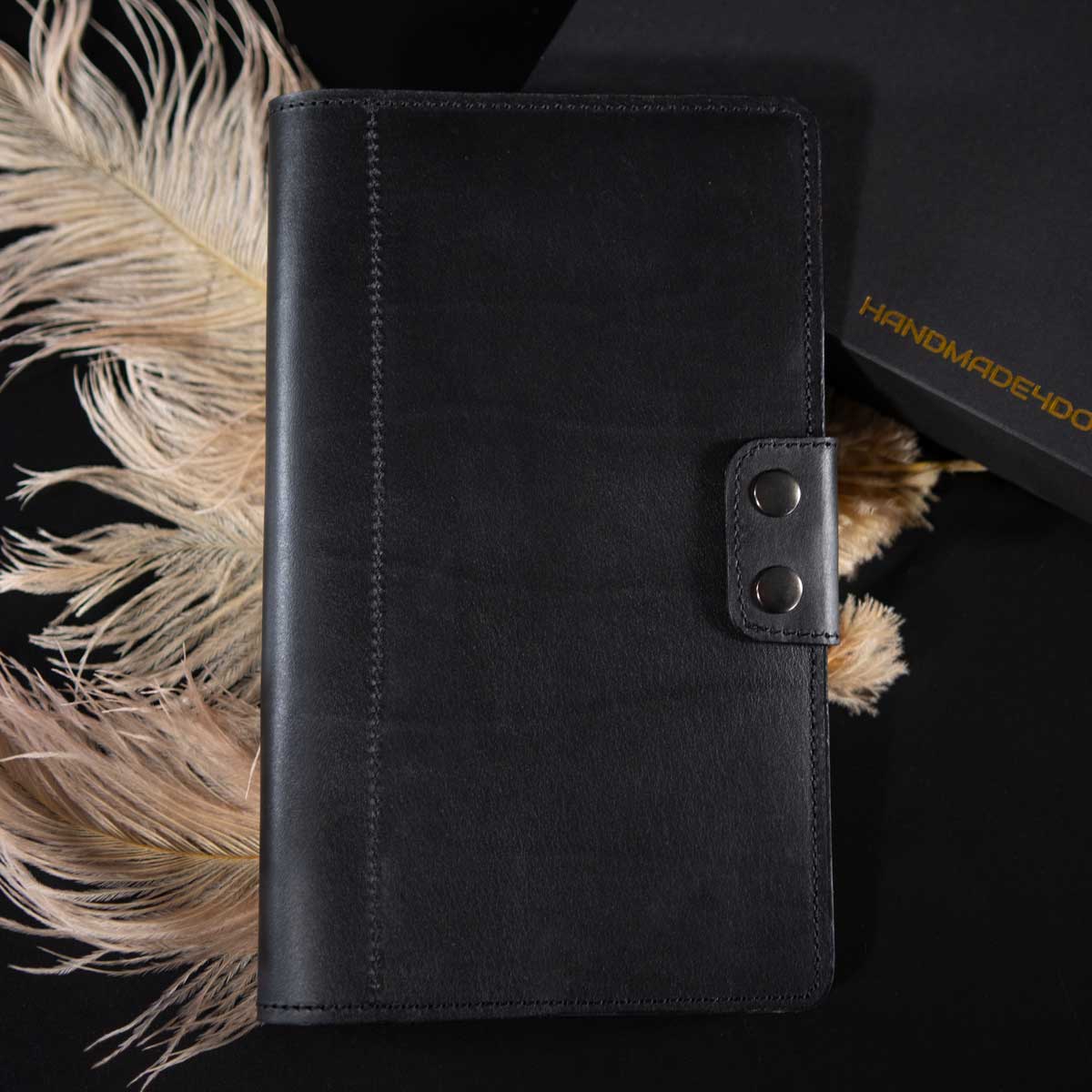 Geschlossenes Travel Wallet für zwei Pässe aus schwerem schwarzem Rindsleder. Die elegante Verschlusslasche mit zwei gunfarbenen Druckknöpfen unterstreicht das puristische Design.