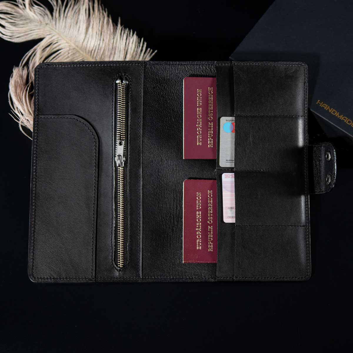 Die geöffnete Innenansicht des befüllten schwarzen Travel Wallets zeigt das edle, feinporige Ziegenleder-Futter, perfekt organisierte Reisepässe, Flugtickets und Kreditkarten.
