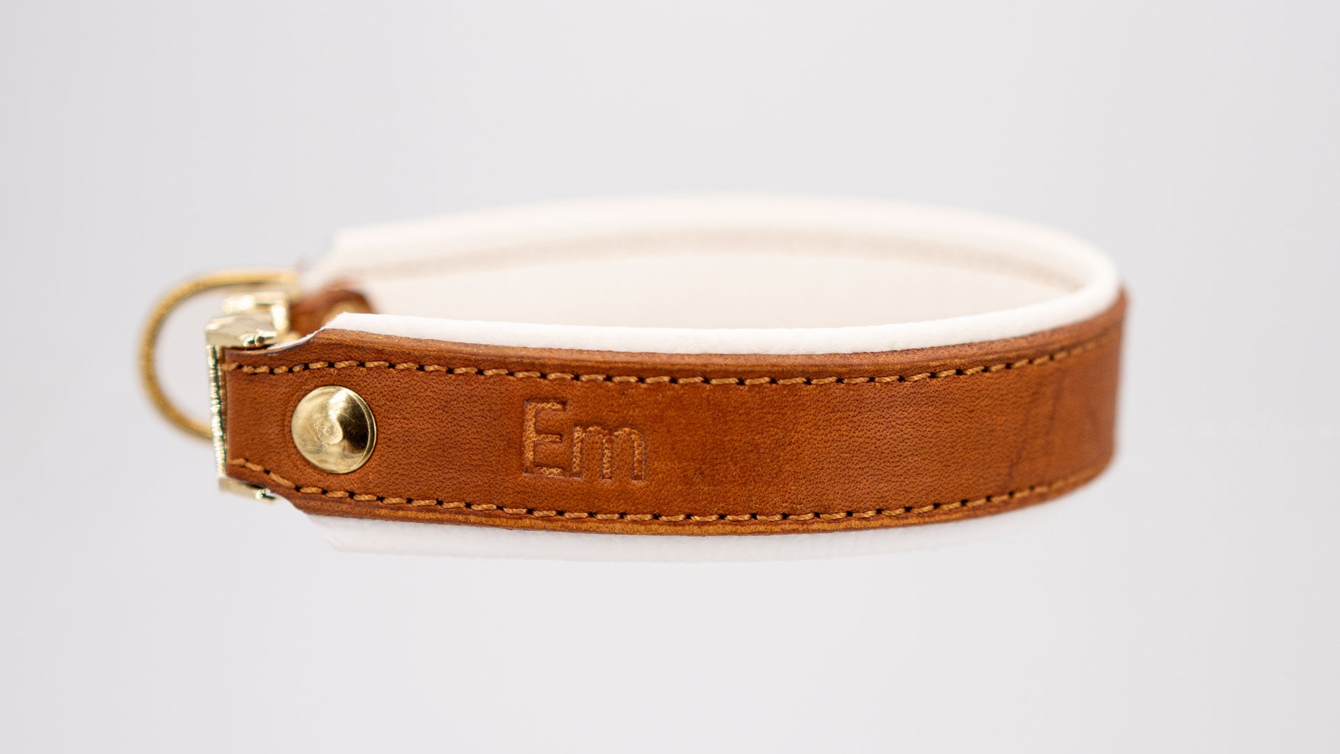 whiskeyfarbenes fettlederhalsband mit weiß hinterlegt, handgefertigt mit messingfarbenen beschlägen, seitlich liegend