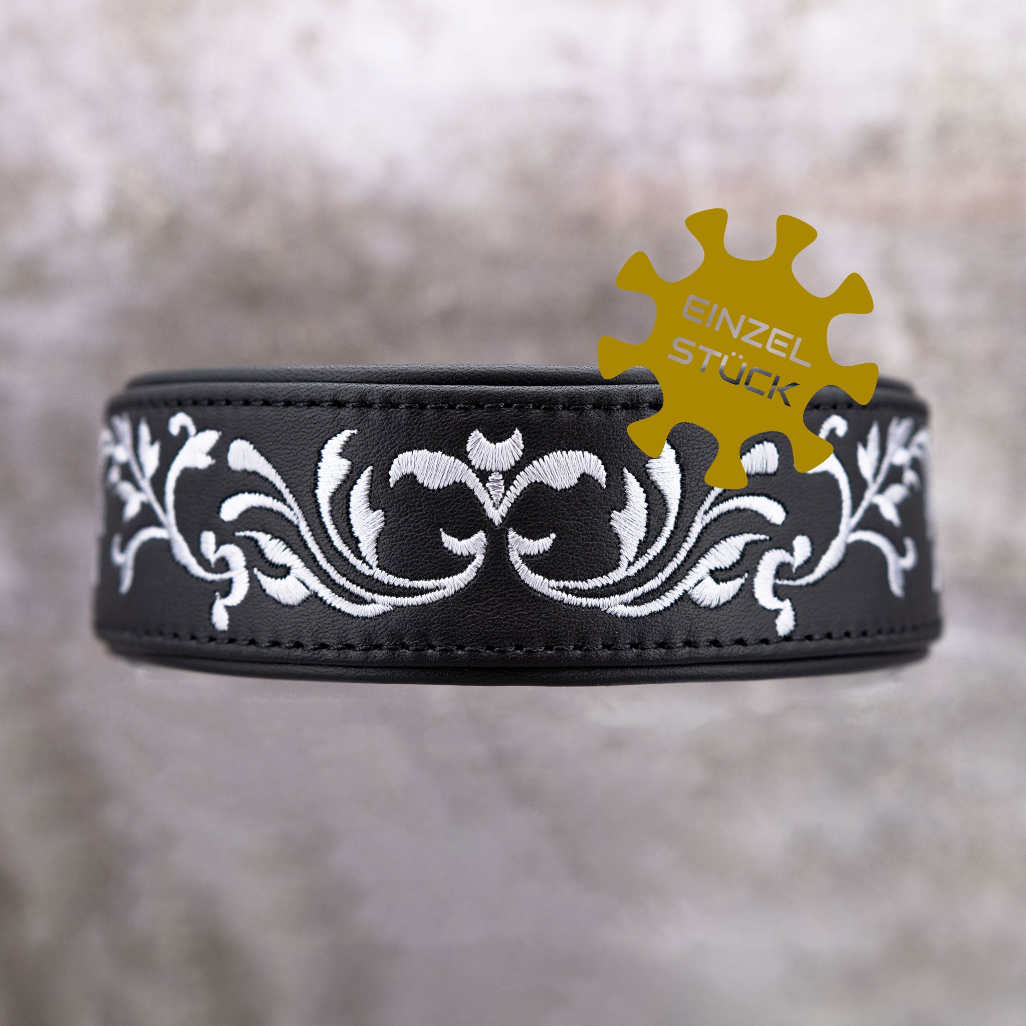 Einzelstueck Detailaufnahme der silbernen Ornament-Bestickung auf schwarzem Rindsnappa