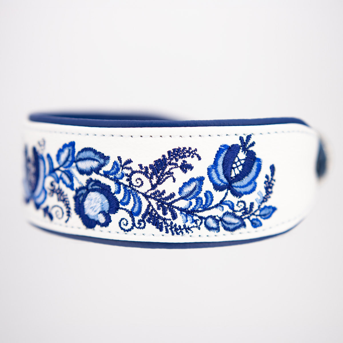 Seitliche Ansicht des handgefertigten Lederhalsbands mit blauer Blumenstickerei und kobaltblauer Lederunterlegung.