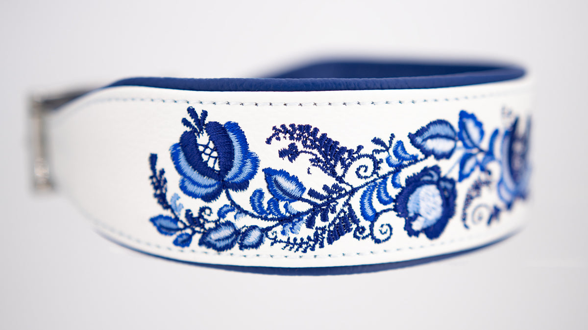 Nahaufnahme der aufwendigen Gzhel-Stickerei mit kobaltblauen Blüten und hellblauen Blättern auf doppelt gebugtem weißem Leder.
