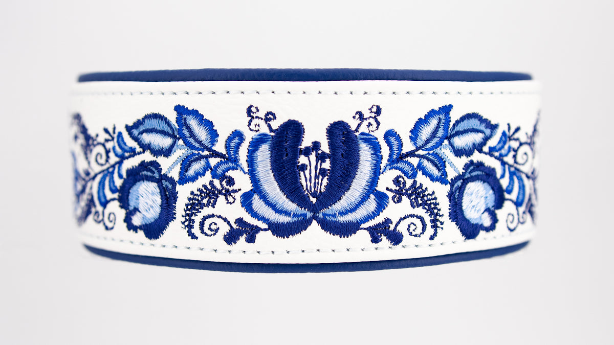 Nahaufnahme der aufwendigen blau-weißen Gzhel-Stickerei mit Blüten, Blättern und feinen Ornamenten auf weißem Leder.