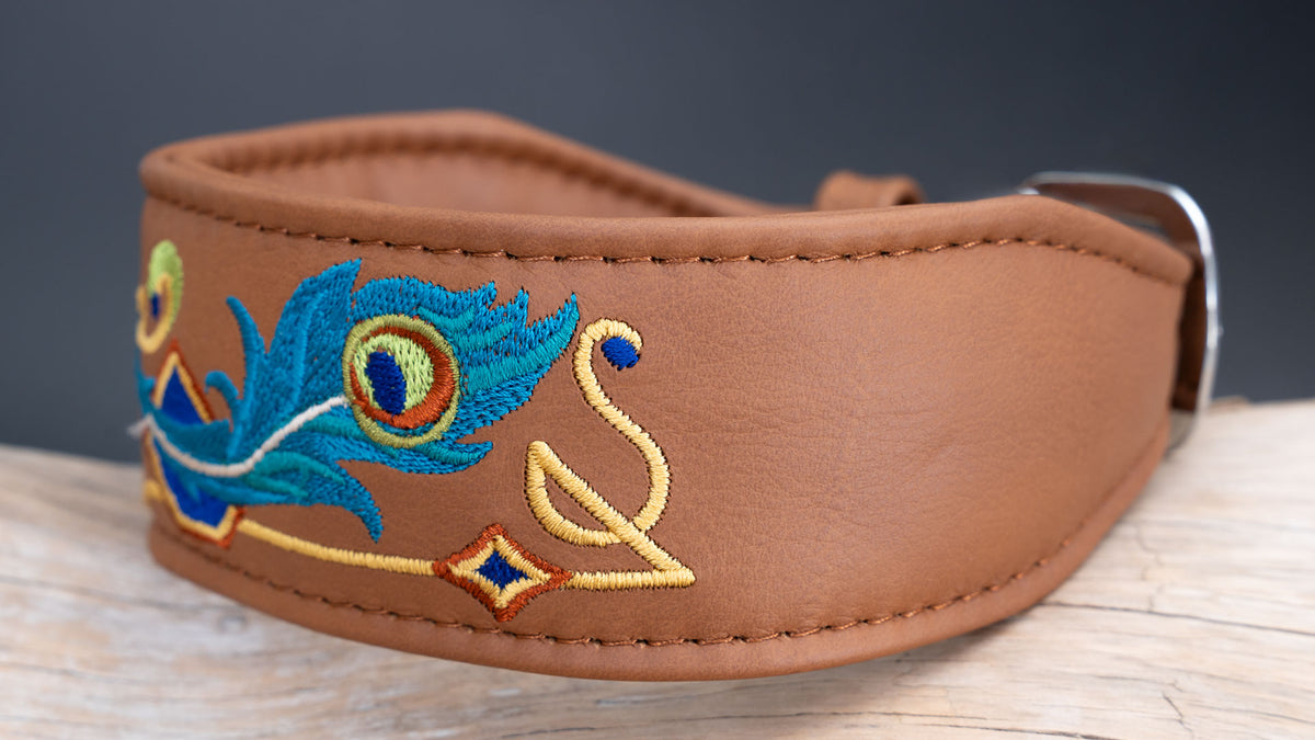Seitenansicht des gepolsterten Windhundhalsbands mit Pfauenfeder-Stickerei auf haselnussbraunem Leder und verjüngter Halsbandform